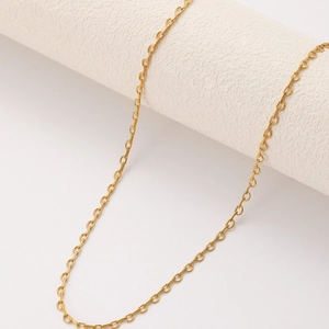 Minimalist golden stainless steel semi-circle tassel necklace on a textured stand