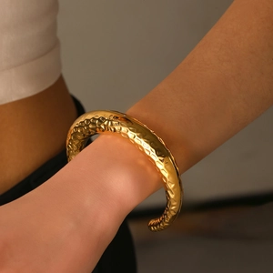 Detailed view of wide gold-plated cuff bracelet with hammered texture finish for women