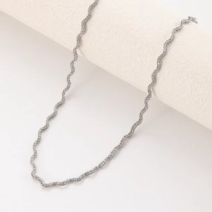 Collier chaîne torsadée en acier inoxydable argenté sur un support minimaliste