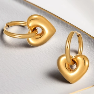 Polished 18K gold stainless steel hoop earrings with 3D heart charms on a stone surface