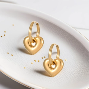 Elegant gold-plated stainless steel heart pendant hoop earrings on a ceramic dish