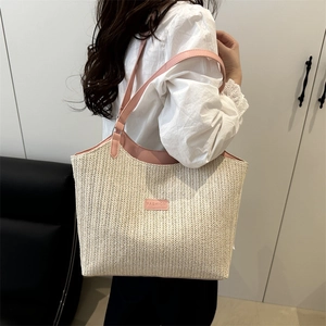 Grande borsa tote in paglia con tracolla rosa indossata da una modella in casa