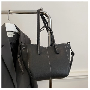 Detail of black pebbled leather tote bag with white contrast stitching on metal rack