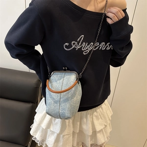 Light blue denim kiss-lock crossbody bag with leather handle and metal chain strap
