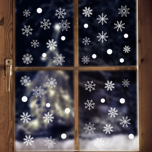 Detail showing white snowflake glass decals on a window with cozy festive light bokeh