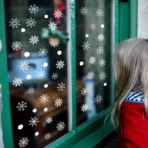 White snowflake window stickers for Christmas decor on green glass window frame