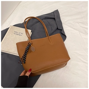 Detail view of brown pebbled leather tote with fashion embossing and tennis racket charm