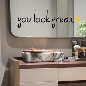 Close-up of You Look Great inspirational quote sticker with sun icon on mirror surface