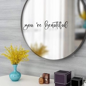 Detail of 'You're Beautiful' inspirational cursive wall sticker on a round bathroom mirror