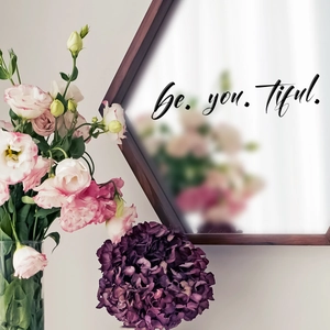 Detail of Be.you.tiful. artistic black vinyl wall sticker on a hexagonal framed mirror