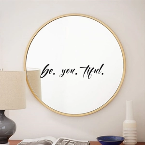 Detail of round gold framed mirror with be.you.tiful. inspirational wall decal art