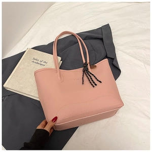 Detail of pink lychee grain tote bag with FASHION logo and striped woven keychain charm