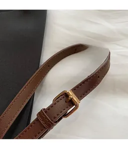 Close-up of adjustable dark brown leather shoulder strap with gold metal buckle detail