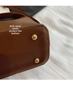 Macro detail of brown leather bucket bag bottom with protective gold anti-wear rivets
