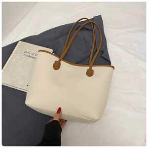 Close-up of beige lychee grain faux leather tote bag with brown contrast trim and handles