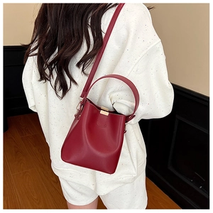 Detail view of a vintage dark red bucket bag with matte leather texture and gold metal buckle