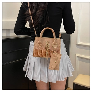 Detail of brown crocodile pattern handbag with metal pendant tassel and small coin purse