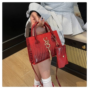 Close-up of red crocodile embossed crossbody bag with gold letter charm and mini pouch