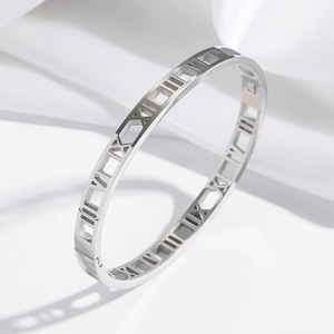 Polished silver stainless steel bangle with cut-out Roman numeral design on silk background