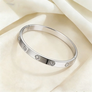 Détail d'un bracelet jonc trèfle argenté avec zircone sur un fond en satin luxueux
