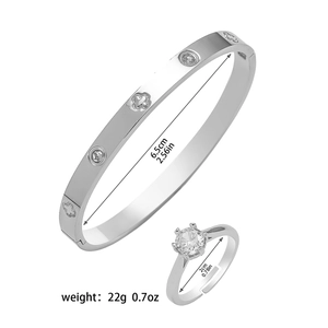 Détail du bracelet trèfle argenté et de la bague en cristal sur fond blanc pur