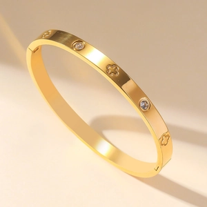 Golden stainless steel clover bangle with crystals shown at a 45-degree angle