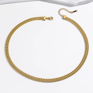 Détail d'un collier en métal tressé doré avec fermoir mousqueton et chaîne d'extension réglable