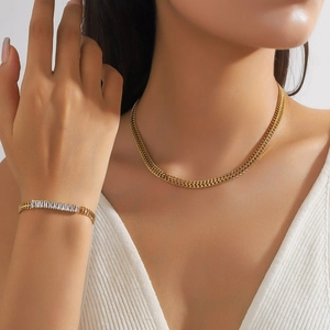 Parure collier et bracelet tressés dorés avec pierres de zircone portés par un modèle