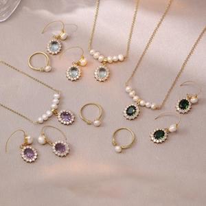 Elegant gold jewelry set with colorful gemstones and pearls on champagne silk fabric