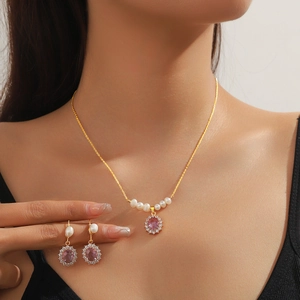 Elegant gold-tone jewelry set with oval purple crystals, pearls and sparkling zircons
