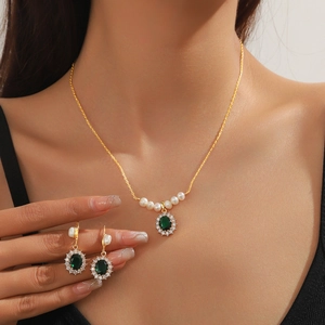Close-up of gold necklace and emerald zircon earrings set worn by a female model