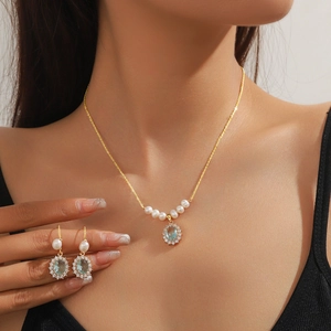Detail of elegant gold necklace and earrings set featuring pearls and blue gemstones