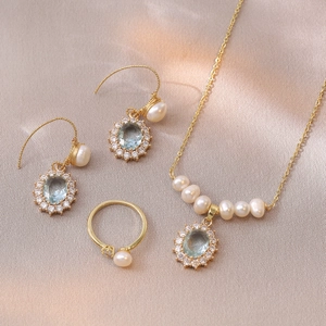 Detailed set of gold necklace, earrings and ring with blue stones and white pearls