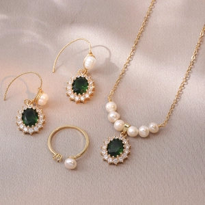 Detail view of emerald green zircon necklace and earring set on champagne silk fabric