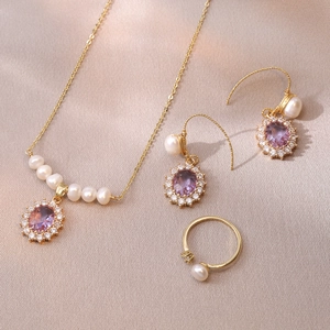 Detail of luxury jewelry set with purple gemstones and pearls on champagne silk