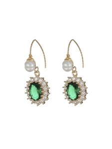 Detailed macro of gold drop earrings with oval emerald zircon and dangling white pearls