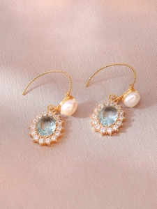 Detail of drop earrings featuring light blue oval zircon and teardrop pearl on pink satin