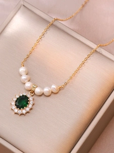 Detailed view of emerald zircon flower pendant with freshwater pearls on a gold necklace