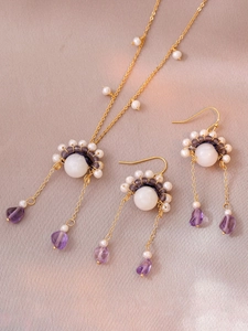Detail van zoetwaterparelketting met paarse druppelstenen en gouden schakels sieraden