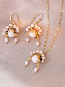Detailopname van retro zoetwaterparelketting en gouden draadoorbellen op zijden stof