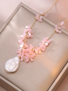 Detail of pink crystal flower necklace with large baroque pearl on a gold chain