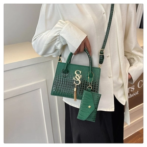 Detail of emerald green crocodile pattern crossbody bag set with gold metal logo on model