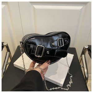 Détail du sac à main noir en forme de cœur avec boucle argentée et bandoulière chaîne