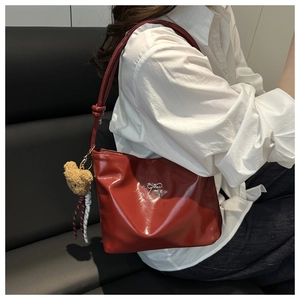Detail der weinroten Lackleder-Beuteltasche mit Silberschleife und Bärenanhänger