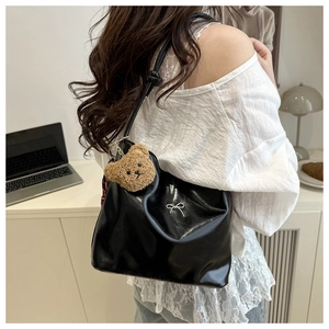 Detail of black faux leather bucket bag with silver bow and plush bear keychain