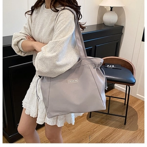 Detail view of a grey canvas tote bag with drawstring closure and Fashion label decoration