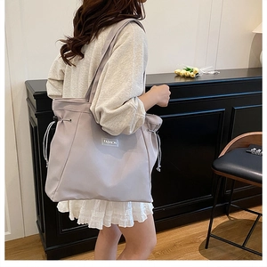 Detailed side view of lavender tote bag featuring adjustable drawstring and fashion label