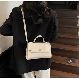 Detail of cream white leather handbag featuring gold metallic logo and smooth finish