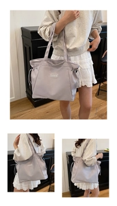 Detail of light grey tote bag featuring adjustable side drawstrings and fashion patch label