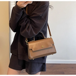 Close-up of brown faux leather shoulder bag featuring metal logo and adjustable strap
